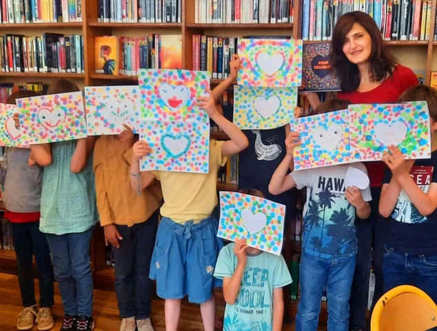 Children showing their drawings in a library
